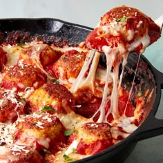 someone is taking a slice of deep dish pizza from a skillet with melted cheese and tomato sauce