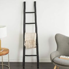 a ladder leaning up against a wall next to a chair and table with a lamp on it