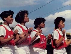 four women in red and white uniforms standing next to each other with their hands together