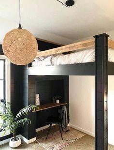 a loft bed with a desk underneath it and a hanging plant in the corner next to it