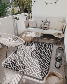 a white couch sitting on top of a patio next to a black and white rug