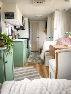 the interior of a small home with green cabinets and white furniture, including a couch