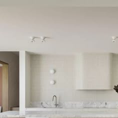 a kitchen with marble counter tops and white tile backsplash, along with two sinks