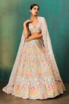 Ivory base lehenga with floral applique all over, highlighted with sequin, pipes and cutdana. Paired with a coordinating blouse, accentuated with all over flower applique in pastel sequin embellishments. Comes along with a dupatta.
Components: 3
Pattern: Applique
Type Of Work: Flower,Sequin,Cutdana
Neckline: Plunging V Neck
Sleeve Type: Sleeveless
Fabric: Soft Organza, Net, Lining: Shantoon
Color: Ivory
Other Details: 
Attached lining
Crystal sphere ornamented latkan
Cut-work trim, flower embroi Aneesh Agarwaal, Ivory Lehenga, Indian Designs, Floral Lehenga, Mehndi Design Images, Ivory Flower, Indian Woman, Flower Soft, Lehenga Blouse