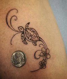 a close up of a tattoo on the side of a person's arm with a coin