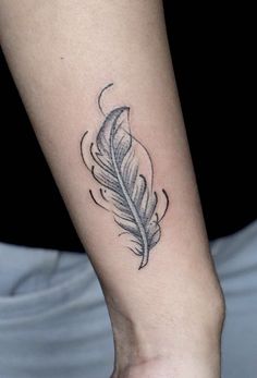 a black and white feather tattoo on the arm