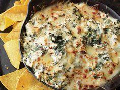 spinach and cheese dip with tortilla chips on the side in a cast iron skillet