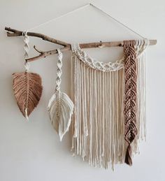 three macrame dream catchers hanging on a wall next to a branch with leaves