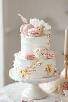 a three tiered white cake with pink and gold decorations