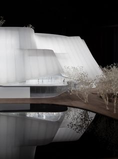 an architectural model of a white building with trees in the foreground and water reflecting on the ground