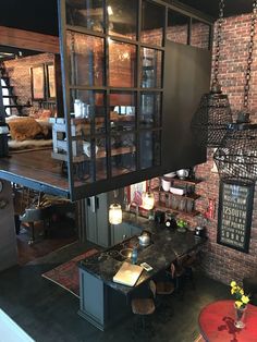 an industrial loft apartment with exposed brick walls and glass doors on the upper floor, open kitchen to dining area