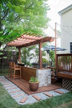 an outdoor kitchen is built into the side of a house with a wooden deck and pergolated patio area