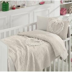 there is a white crib with a blanket and pillows on it in the room