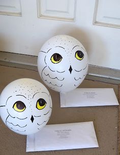 two white eggs with yellow eyes sitting on the ground next to each other in front of a door