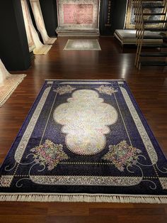 a large blue rug on the floor in a room with wooden floors and black walls