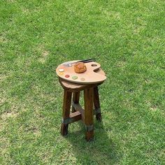 a small wooden table sitting on top of a lush green grass covered field next to a knife and fork