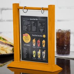 a menu board sitting on top of a table next to a plate of food and drink