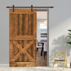 an open barn door in a room with a chair and potted plant on the floor