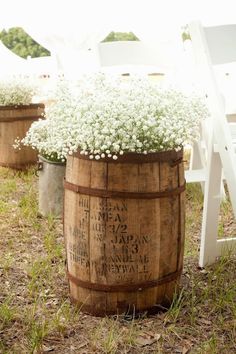 a wooden barrel filled with baby's breath sitting on top of a grass covered field