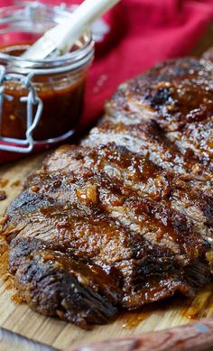 a steak on a cutting board next to a jar of bbq sauce