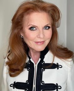 a woman with long red hair wearing a white jacket and black trimming on her collar