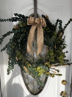 a wreath on the front door is adorned with greenery and burlocked bow