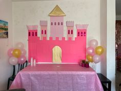 a pink castle table with balloons on it