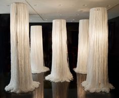 four tall white vases sitting on top of a black table