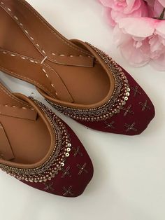 a pair of red shoes sitting on top of a white table next to pink flowers