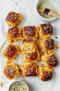 rolls with cheese and poppy seed sprinkles on a white plate next to a small bowl of dipping sauce