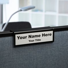 an office cubicle with a name plate attached to the back of it and a microphone in the background