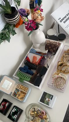 a table topped with lots of different types of rings and bracelets next to a vase filled with flowers