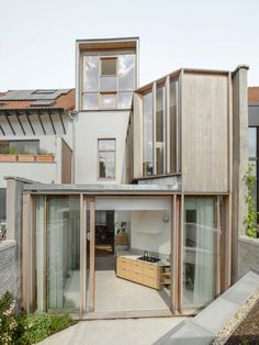 a modern house with large glass windows and wooden sidings on the side of it