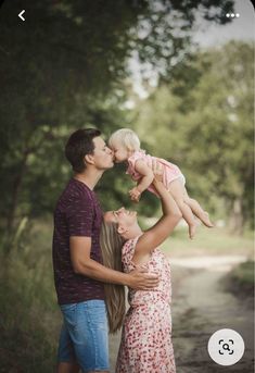 a man and woman holding a baby in the air while standing next to each other