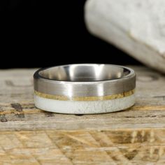 a close up of a wedding ring on top of a piece of wood with a rock in the background