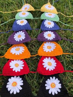 several crocheted hats with flowers on them are hanging from a line in the grass