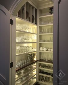 an open pantry with wine glasses and other items in the shelves on top of it