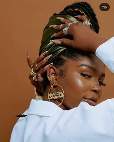 a woman with large gold hoop earrings on her head, wearing a white shirt and holding a palm leaf