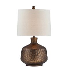 a table lamp with a white shade on the base and a brown metal vase underneath it