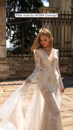 a woman in a wedding dress is walking down the street with her long veil over her shoulder