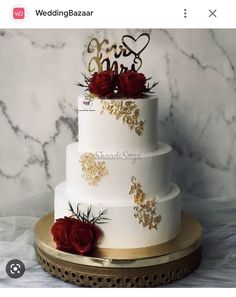 a three tiered wedding cake with red roses on top