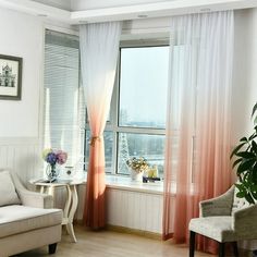 a living room filled with furniture next to a window covered in sheers and curtains