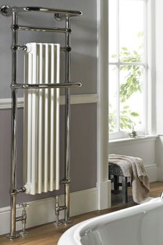 a white bath tub sitting next to a window in a bathroom under a radiator