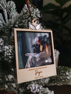 an ornament hanging from a christmas tree with a photo in the frame on it