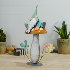 a ceramic mushroom with two birds perched on it's top sitting next to potted plants