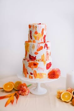 a three tiered cake with oranges and flowers on the table next to it