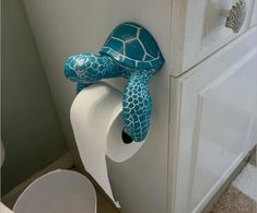 a turtle shaped toilet paper dispenser on the side of a bathroom cabinet