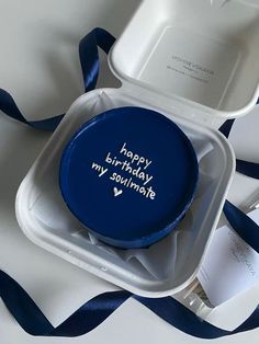 a blue happy birthday cake in a white box with ribbon around it on a table