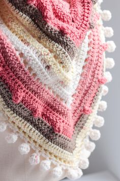 a crocheted shawl with pom - poms on it