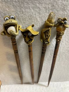 three wooden spoons with carved faces on them, one is frog and the other two are toad